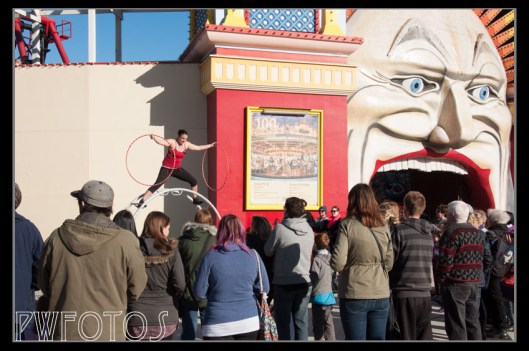 A street acrobat performs to the crowds outside of Luna Park in St Kilda